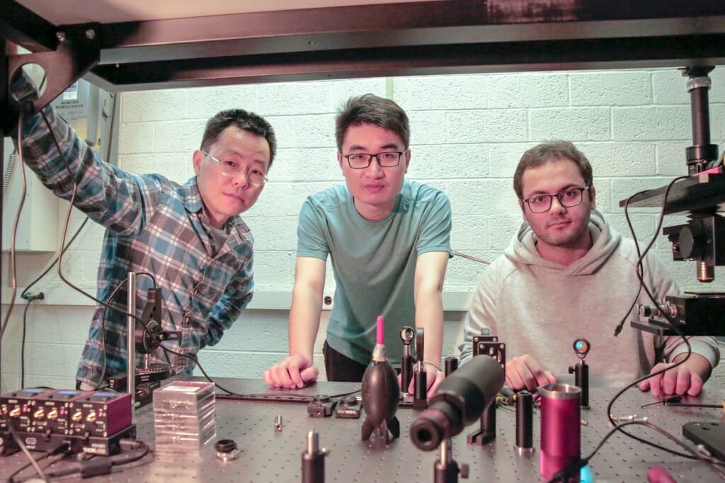 照片:三名研究人员聚集在一个实验室。