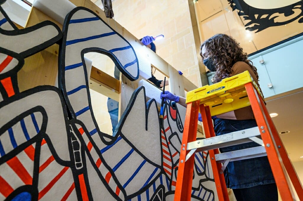 博物馆员工艾玛钉蹄铁工人用艺术家的刷灰尘艺术品的边缘。