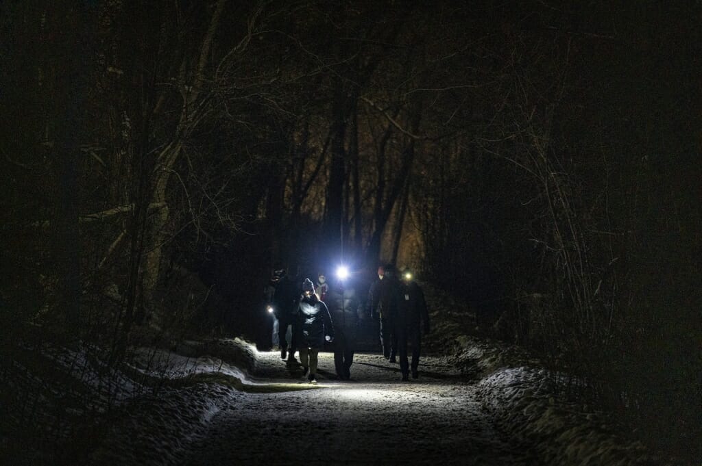 一组参与者穿着前照灯参加一个户外UW night-hike事件走霍华德湖岸的路径。开云体育appios下载