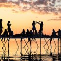 人在夕阳silhoutted坐在码头曼德特湖。