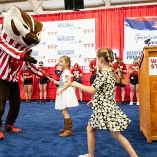 巴基獾穿着红色和白色带衬衫和两个年轻的女孩穿着裙子跳舞时的阶段