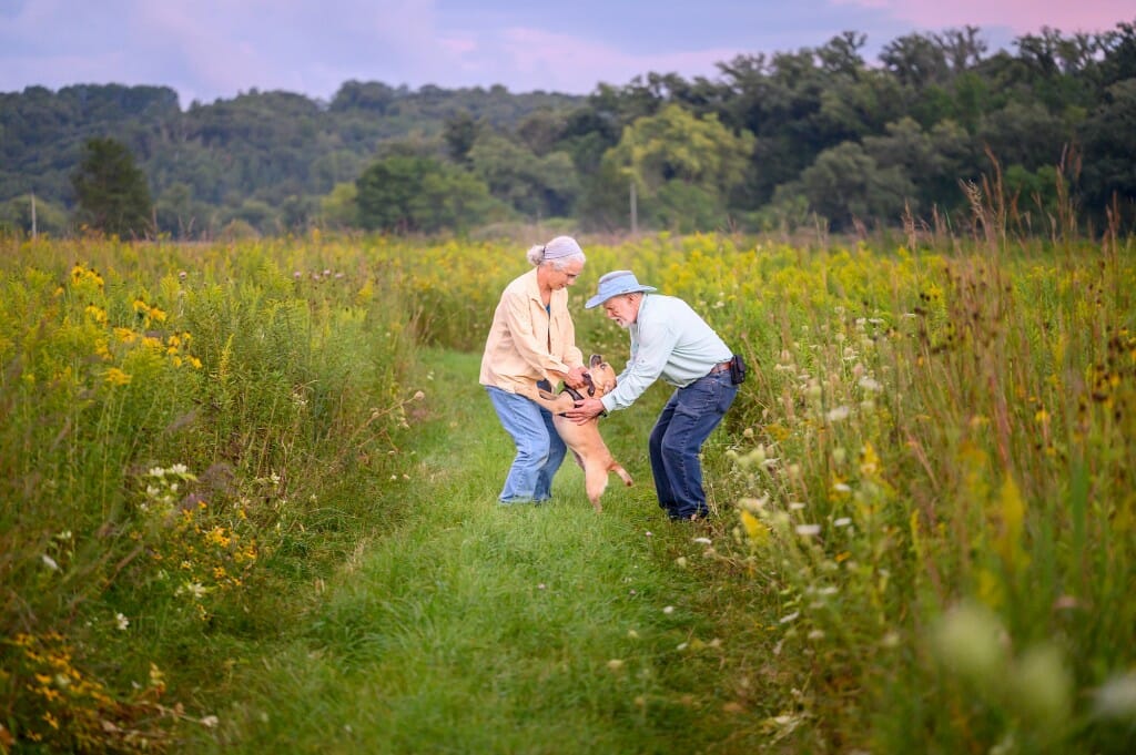 一个女人和一个男人站在草原爱抚一只小狗