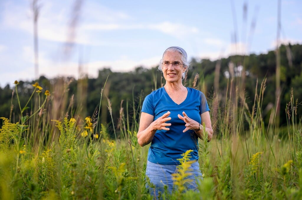 一个女人在一个蓝色的衬衫站在草原用双手和手势。