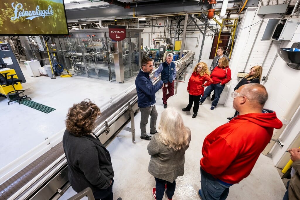 在中间，Shawn Snedden在Linenkugel啤酒厂的生产车间与Jennifer Mnookin和其他人交谈。