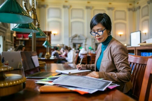莫妮卡金坐在一张桌子在阅览室里的威斯康辛州历史学会。开云体育世界杯微信群她从一堆记笔记,阅读报纸。