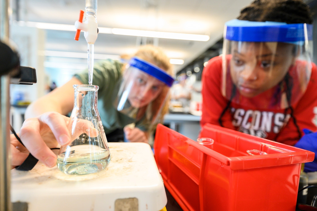 在一堂化学实验课上，两个戴着面罩的学生凑过去，看着烧杯里的液体从蓝色变成黄色。