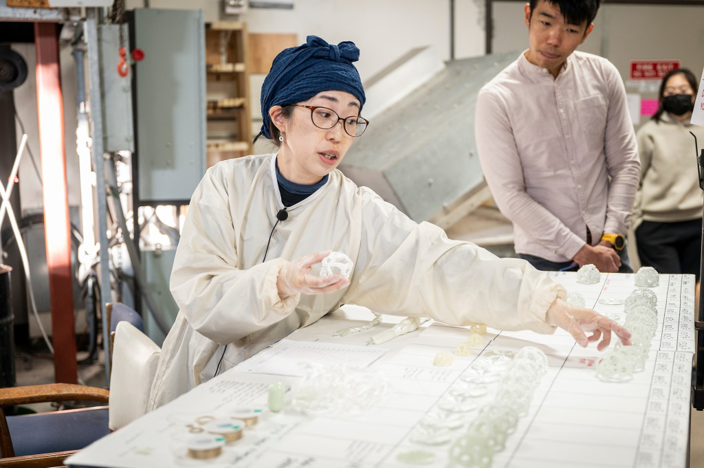 在实验室的玻璃,Machiko Ito戴着防护工作服和处理完成玻璃碎片从一个表中选择。