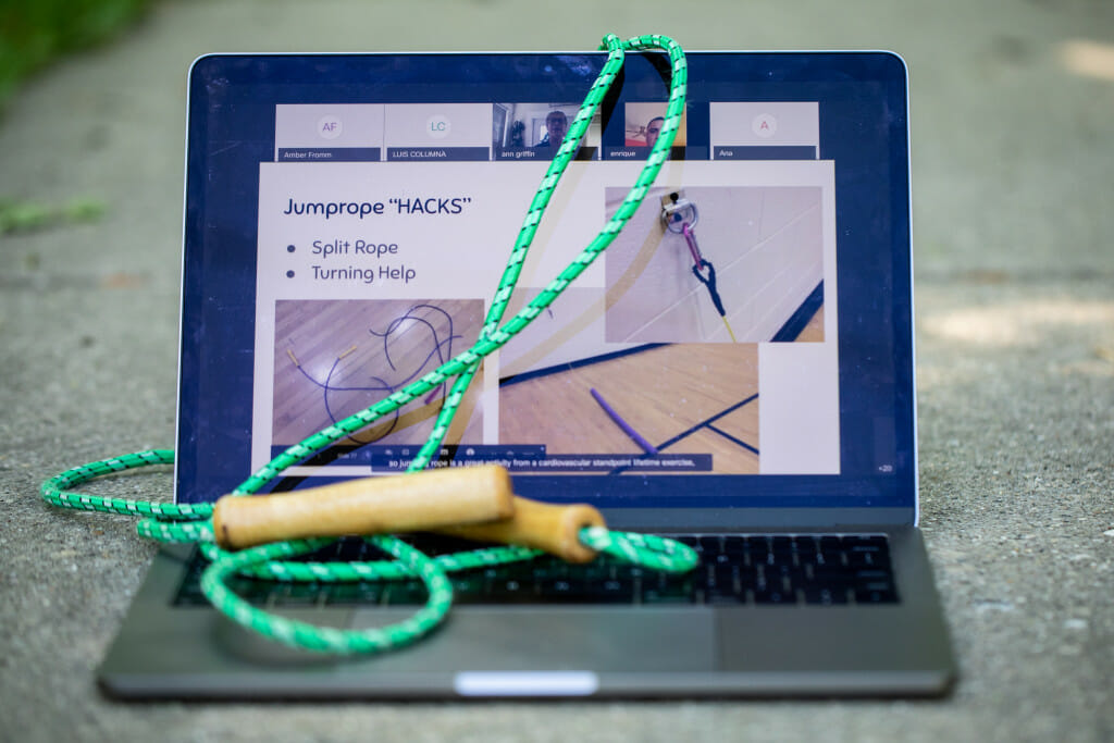 一个开放的笔记本电脑显示一个练习regemin。一个绿色jumprope位于键盘。