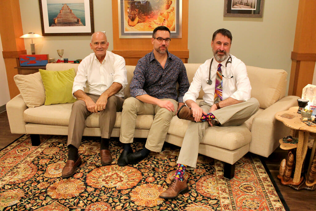 医药学院的教授保罗•Hutson(左)与医学院的助理教授和公共卫生的合作者克里斯托弗·尼古拉斯(中心)和教授兰德尔·布朗(右)坐在沙发奶油,微笑向相机。他们在房间里用于迷幻测试。