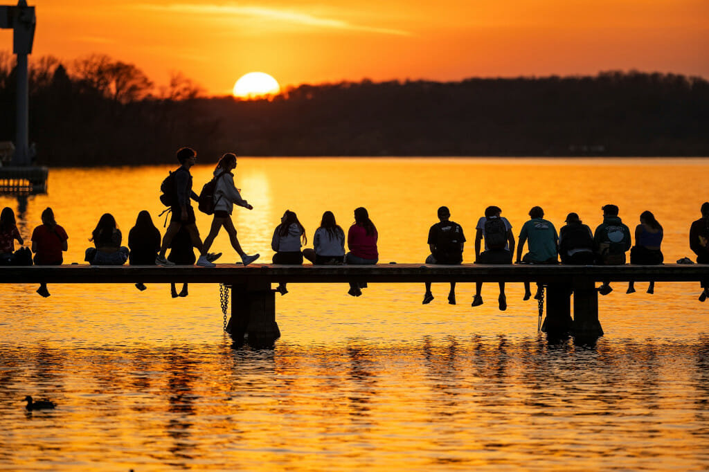走出冬天冬眠,人们行Goodspeed家族码头聊天在春季温暖和看日落摔倒曼德特湖和野餐点(在地平线上)。