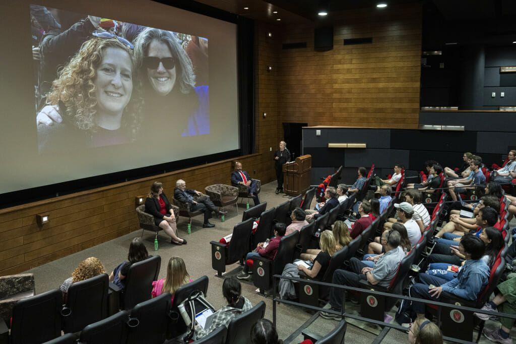 演讲大厅挤满了人看两个女人在大屏幕上的照片。